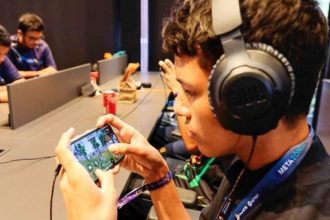 Jogador de Free Fire em evento de games com fone de ouvido e celular.