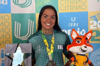 Kathleen Amaral com medalha de bronze no JUBs Praia 2025, segurando um troféu e um mascote.