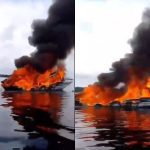 Lancha em chamas no rio Negro, soltando fumaça preta.