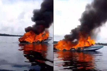 Lancha em chamas no rio Negro, soltando fumaça preta.