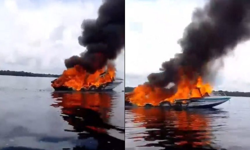 Lancha em chamas no rio Negro, soltando fumaça preta.