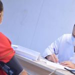 Médico medindo a pressão arterial de uma paciente durante consulta.