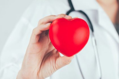 Médico segurando um coração vermelho, simbolizando a saúde cardiovascular no Setembro Vermelho.