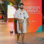Modelo em desfile de moda, vestindo roupa clara e acessórios, em evento Fashion Summer.
