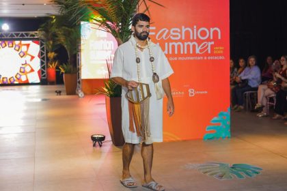 Modelo em desfile de moda, vestindo roupa clara e acessórios, em evento Fashion Summer.
