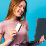 Mulher sorrindo com cartão de crédito e laptop, e-commerce no Amazonas