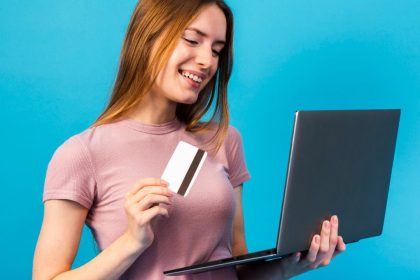 Mulher sorrindo com cartão de crédito e laptop, e-commerce no Amazonas