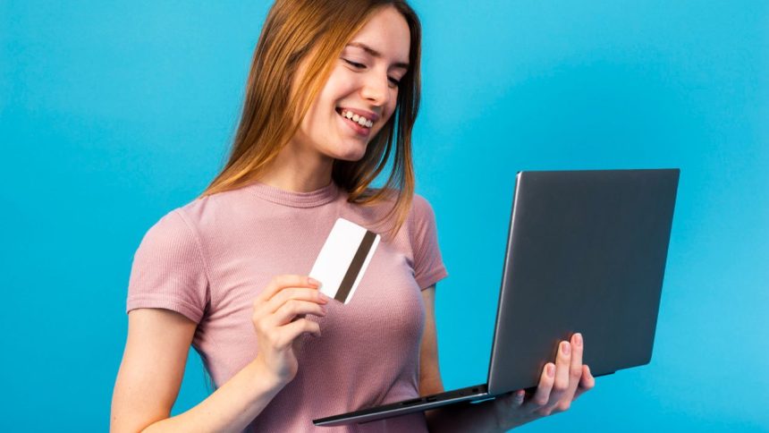 Mulher sorrindo com cartão de crédito e laptop, e-commerce no Amazonas