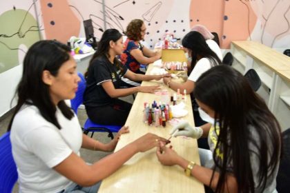 Mulheres em curso de manicure no Cetam, aprendendo e aplicando esmalte nas unhas.