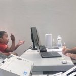 Mutirão jurídico em Coari: Mãe e criança em atendimento, com profissional anotando.