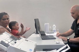 Mutirão jurídico em Coari: Mãe e criança em atendimento, com profissional anotando.