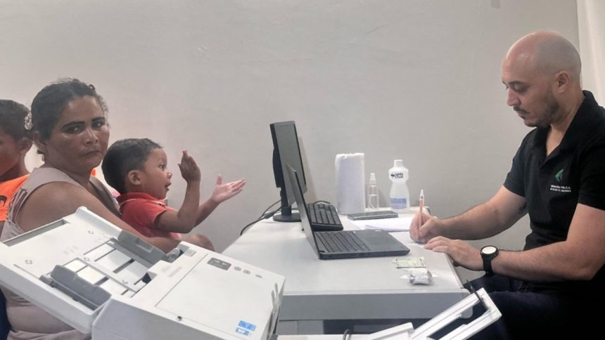 Mutirão jurídico em Coari: Mãe e criança em atendimento, com profissional anotando.