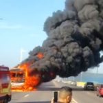 Ônibus em chamas na ponte Jornalista Phelippe Daou, com fumaça preta intensa e ambulância no local.