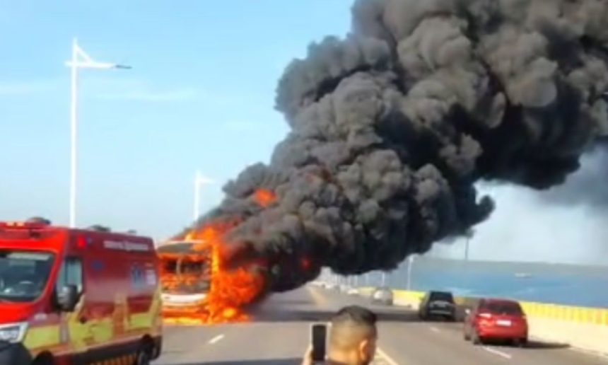 Ônibus em chamas na ponte Jornalista Phelippe Daou, com fumaça preta intensa e ambulância no local.