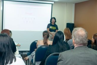 Palestrante em evento de Direito Bancário em Manaus, com tela do Google ao fundo e público atento.