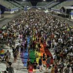 Parada do Orgulho LGBT+ em Manaus com multidão e bandeira arco-íris.