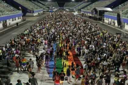 Parada do Orgulho LGBT+ em Manaus com multidão e bandeira arco-íris.