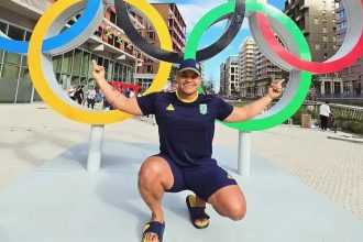 Pedro Nunes posa em frente aos anéis olímpicos, comemorando convocação.