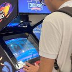 Pessoa joga The King of Fighters em um fliperama durante evento geek em shopping.