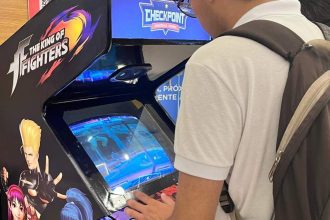 Pessoa joga The King of Fighters em um fliperama durante evento geek em shopping.