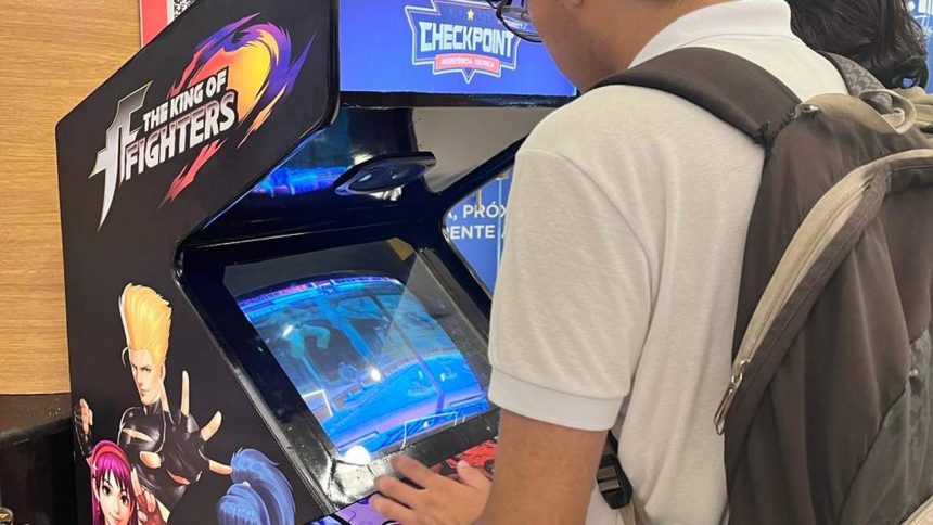 Pessoa joga The King of Fighters em um fliperama durante evento geek em shopping.