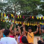 Pessoas de mãos dadas em celebração com decoração festiva ao fundo