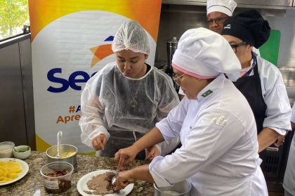 Pessoas em aula de gastronomia no Senac, preparando pratos em uma cozinha.