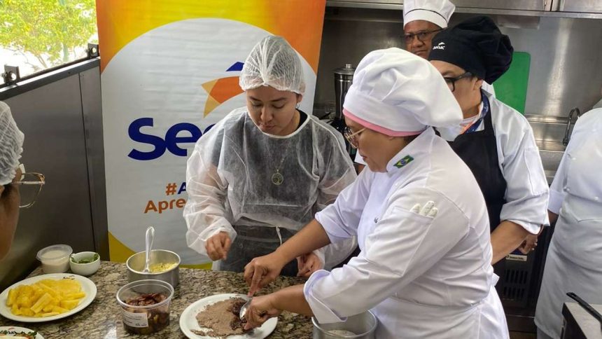 Pessoas em aula de gastronomia no Senac, preparando pratos em uma cozinha.