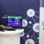 Pessoas em evento com tela mostrando dados de sorteio, incluindo nomes e valores.