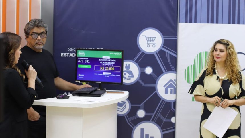 Pessoas em evento com tela mostrando dados de sorteio, incluindo nomes e valores.