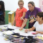 Pessoas em evento recebendo pulseiras, com informações sobre o festival e a data 27/05/2024.