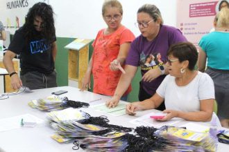 Pessoas em evento recebendo pulseiras, com informações sobre o festival e a data 27/05/2024.