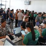 Pessoas em fila e atendentes em evento da Afeam (Agência de Fomento do Amazonas).