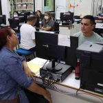 Pessoas em um escritório com computadores, possivelmente um processo seletivo da Seduc.