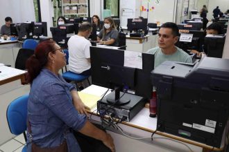 Pessoas em um escritório com computadores, possivelmente um processo seletivo da Seduc.