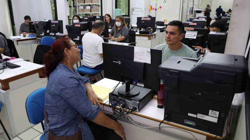 Pessoas em um escritório com computadores, possivelmente um processo seletivo da Seduc.