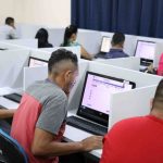 Pessoas fazendo prova eletrônica em computadores, em sala de aula, Provão EJA Amazonas