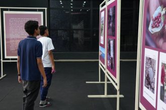 Pessoas observando fotos na exposição Olhares da Amazônia em Manaus.