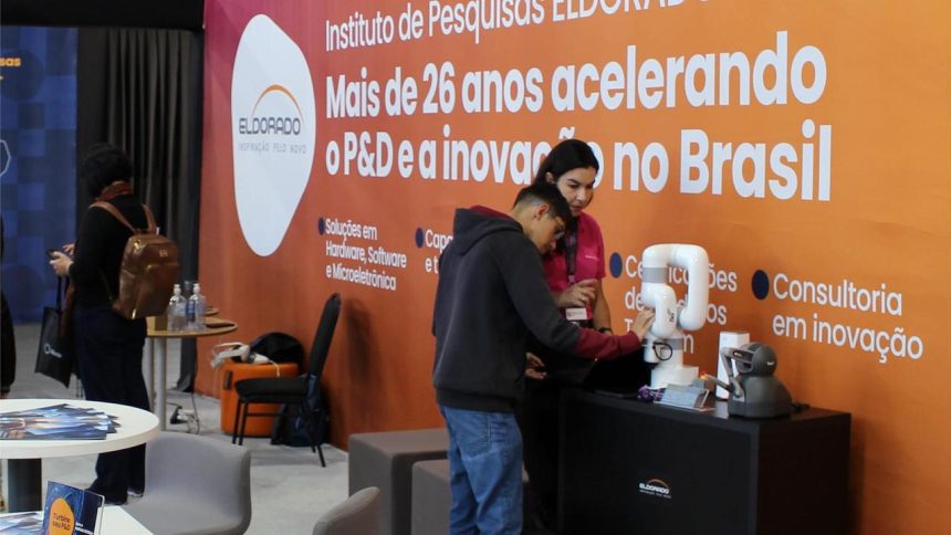 Pessoas observando robôs em um estande do Instituto Eldorado, com logotipo em destaque. Foco em inovação e tecnologia.