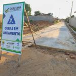 Placa 'Obras em andamento' em rua em construção em Canutama, Amazonas.