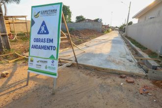 Placa 'Obras em andamento' em rua em construção em Canutama, Amazonas.