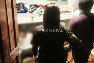 Policial com camisa preta com a escrita 'Polícia Civil' em uma investigação.