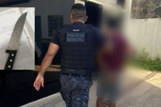 Policial com colete da Polícia Municipal prendendo homem com faca em cena.