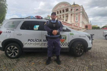 Policial militar em frente a viatura com o Teatro Amazonas ao fundo.