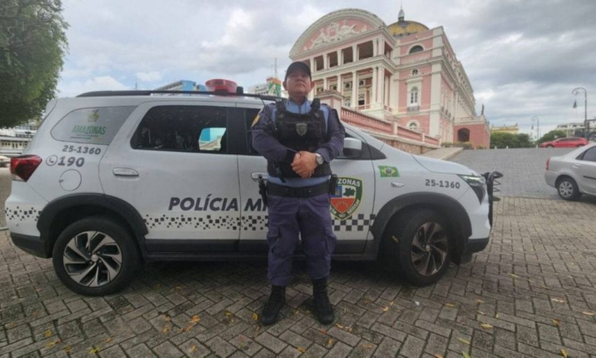 Policial militar em frente a viatura com o Teatro Amazonas ao fundo.