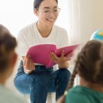 Professora asiática lendo para crianças em sala de aula
