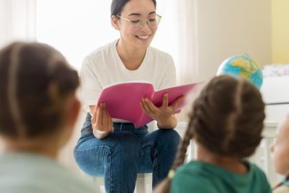 Professora asiática lendo para crianças em sala de aula