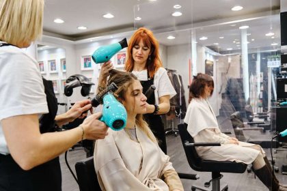 Profissionais de beleza trabalhando em um salão, usando secadores de cabelo.