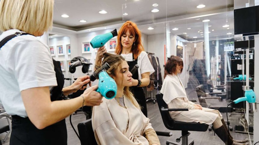 Profissionais de beleza trabalhando em um salão, usando secadores de cabelo.