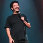 Rodrigo Marques sorrindo com microfone em show de stand-up